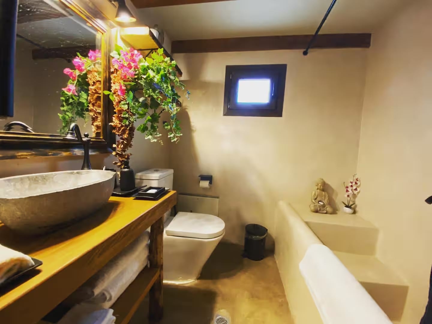 The indoor bathroom, with a stone basin on a wooden counter and plastered walls