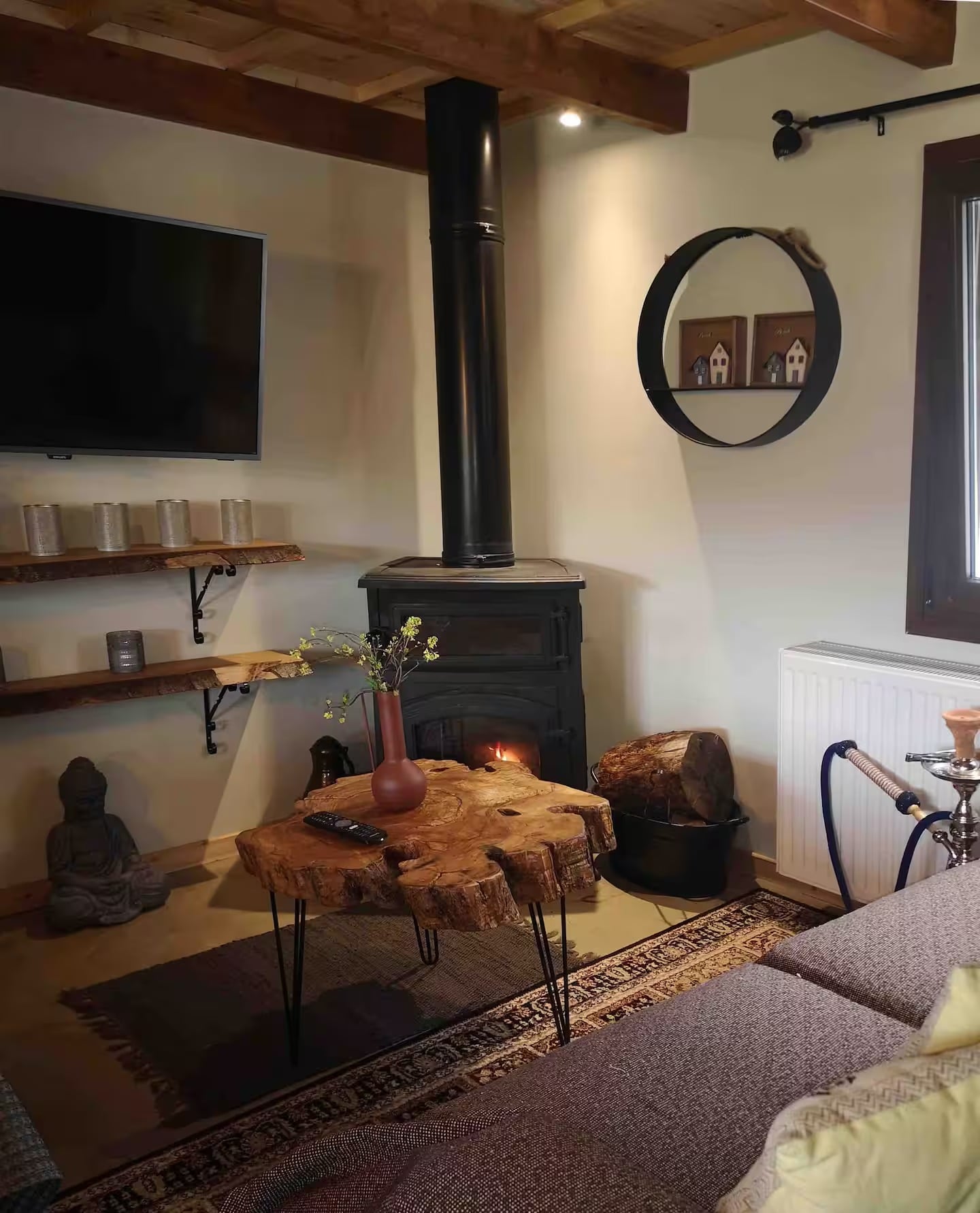 The living room, with the wood-burning stove lit, a live-edge coffee table and a sofa