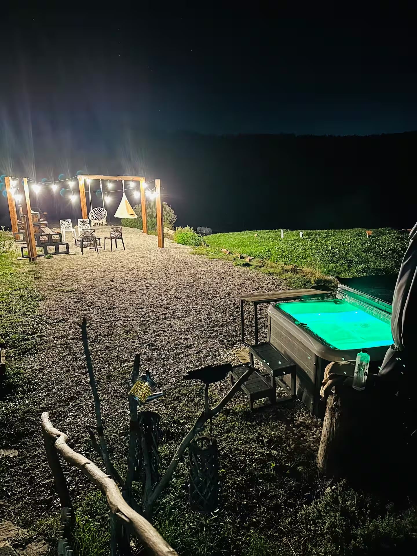 The garden at night, with string lights over the seating area and the hot tub lit up